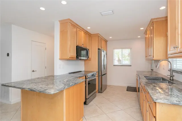 a kitchen with granite countertop a sink a window and cabinets