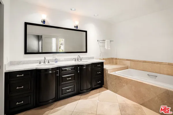 a bathroom with a tub sink double vanity and mirror