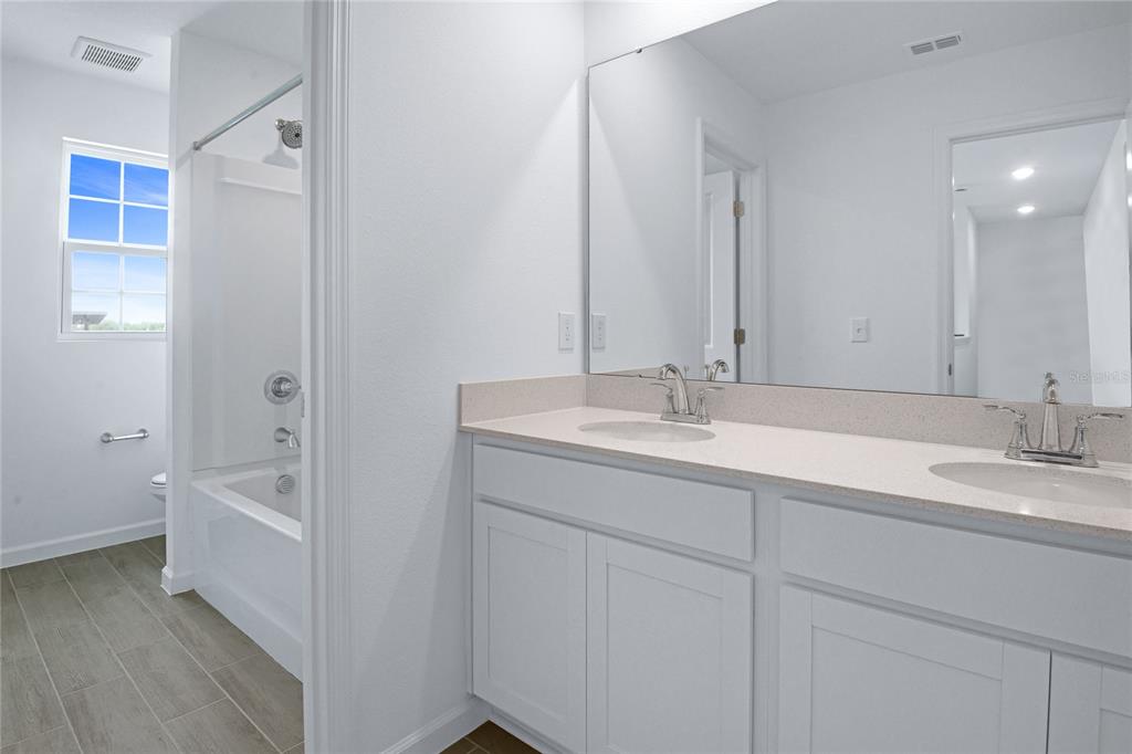 236 Flag Lilly Lane Umatilla, FL 32784 - Photo 13 of 25 a bathroom with a double vanity sink a mirror and a bathtub