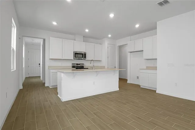 a kitchen with kitchen island a sink a stove a refrigerator and white cabinets