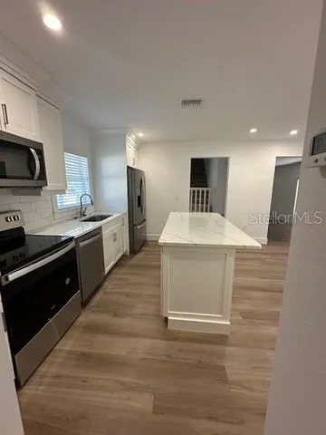 a kitchen with stainless steel appliances kitchen island sink refrigerator and stove