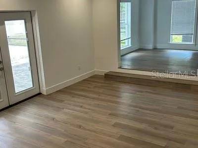 a view of an empty room with window and wooden floor