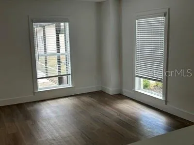 an empty room with wooden floor and windows