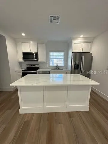 a view of kitchen with wooden floor and electronic appliances