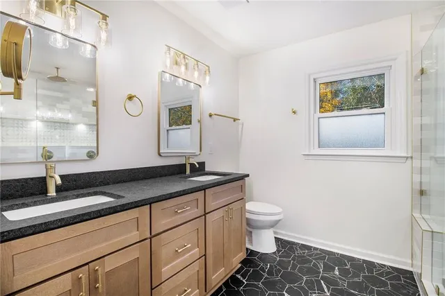 a bathroom with a granite countertop sink toilet and mirror