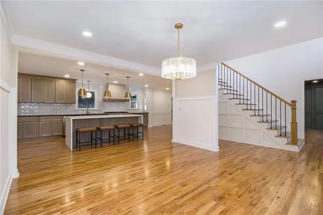 a kitchen with stainless steel appliances kitchen island granite countertop a table chairs and a wooden floor
