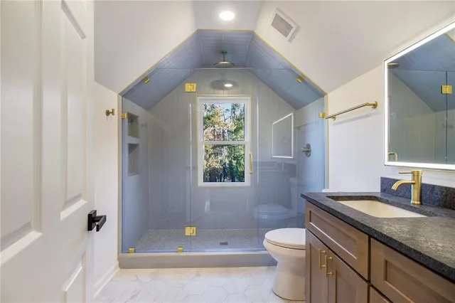 a bathroom with a granite countertop toilet a sink and a mirror