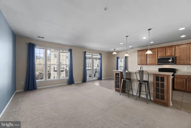 a view of an empty room with kitchen and window