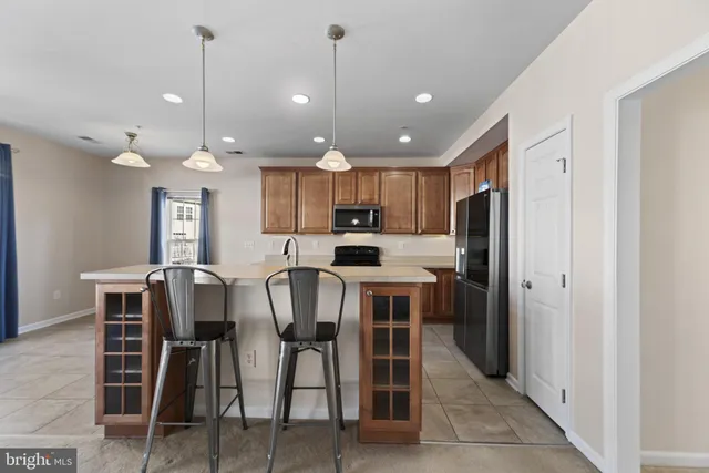 a kitchen with kitchen island a dining table chairs stainless steel appliances and cabinets