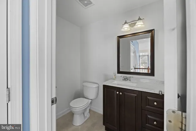 a bathroom with a toilet sink vanity and mirror