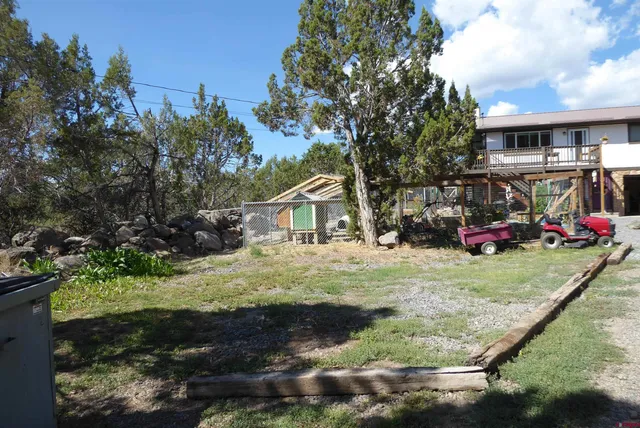 a view of a wooden house with a large tree in the background