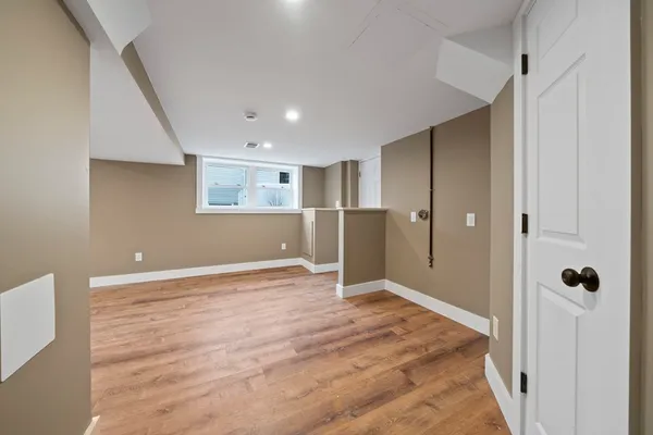 a view of an empty room with wooden floor and a bathroom