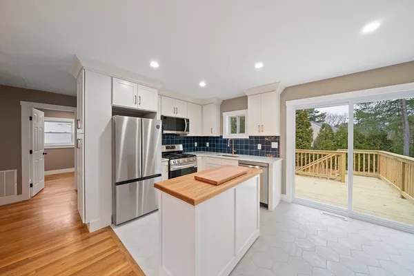 a kitchen with refrigerator a sink and a stove with wooden floor