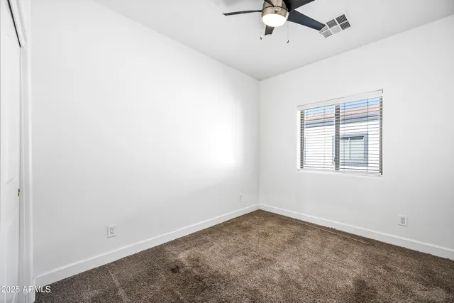 an empty room with a window and a fan