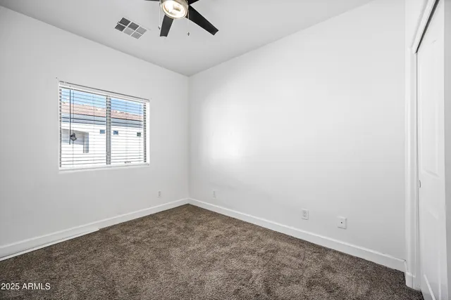 an empty room with a window and a ceiling fan