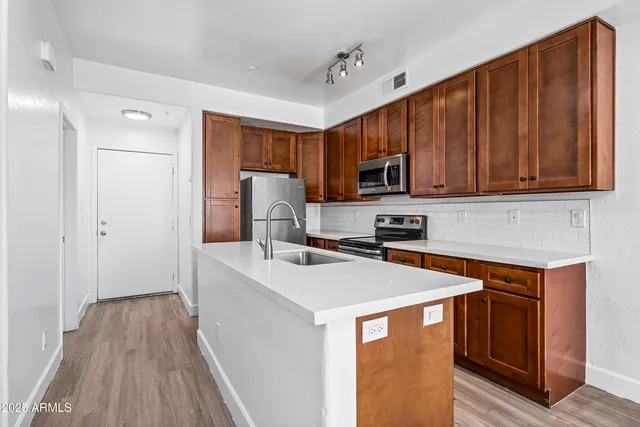 a kitchen with stainless steel appliances granite countertop a refrigerator a stove a sink dishwasher and a microwave oven with wooden floor