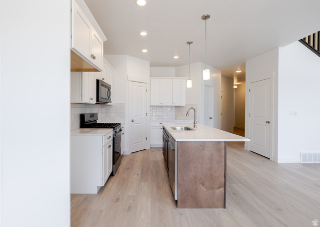 4748 Heartwood Road, Unit 434 Mapleton, UT 84664 - Photo 8 of 18 Dual tone kitchen featuring stainless steel appliances, dual tone cabinetry, a kitchen island with sink, light wood-style floors, and light stone countertops