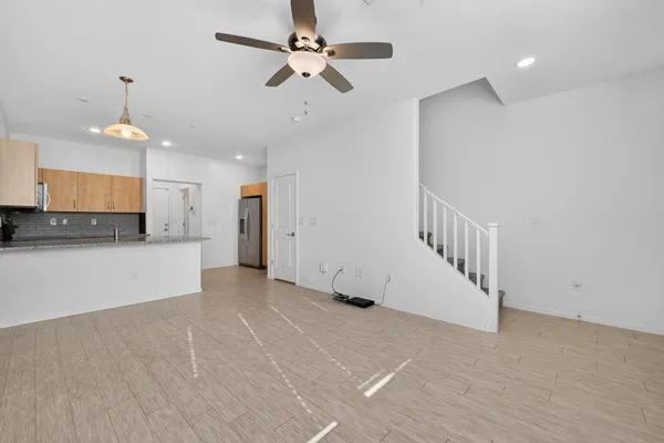 a view of an empty room with kitchen and a chandelier fan