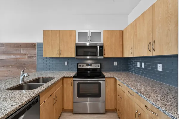 a kitchen with granite countertop a sink stove and microwave