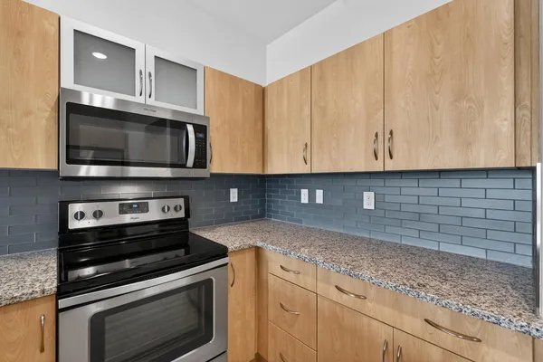 a kitchen with stainless steel appliances granite countertop grey cabinets a stove a sink and dishwasher