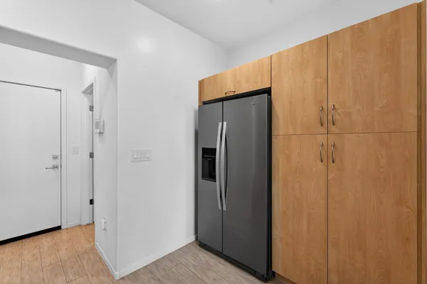 a view of a refrigerator in kitchen island a sink and cabinets