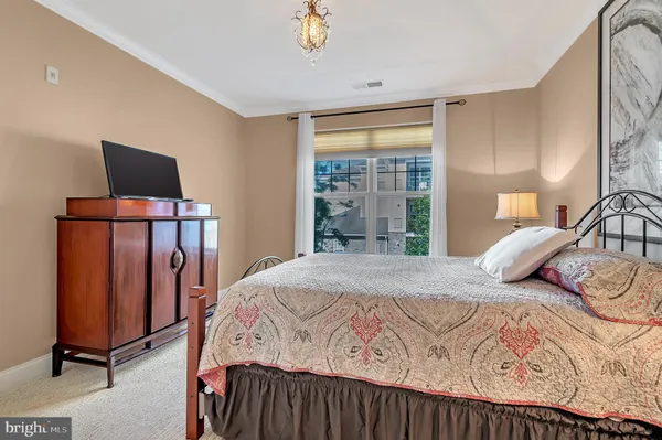 a bedroom with a bed and a flat tv screen on dresser