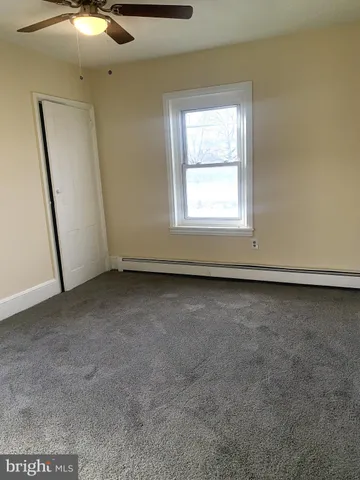 an empty room with a ceiling fan and window