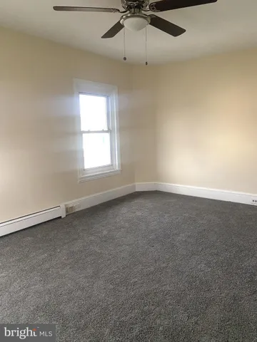 an empty room with a window and a fan