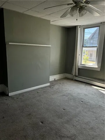 an empty room with a ceiling fan and window