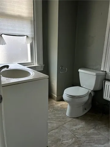 a bathroom with a granite countertop toilet and a sink