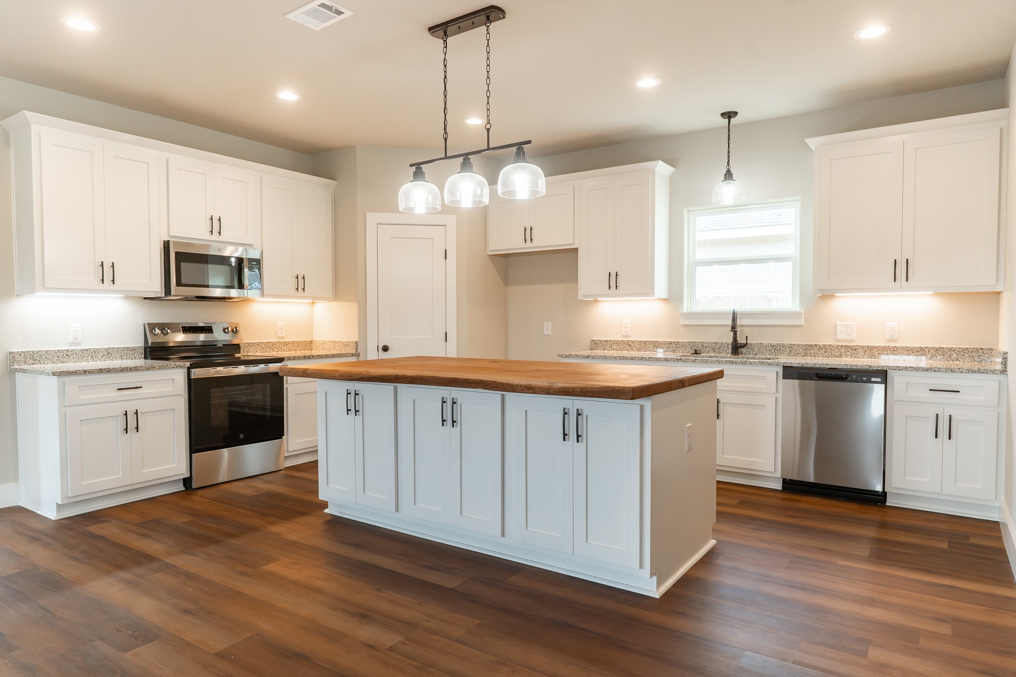 305 String Prairie Way Smithville, TX 78957 - Photo 6 of 26 a kitchen with stainless steel appliances granite countertop a sink a stove a refrigerator and a oven with wooden floor