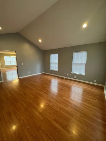 a view of an empty room with window and wooden floor