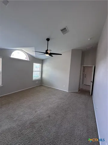 en empty room with windows and ceiling fan