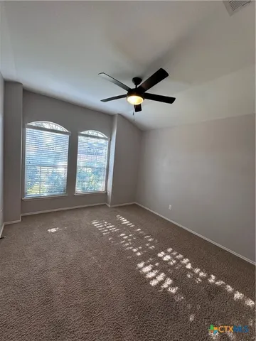 an empty room with windows and ceiling fan