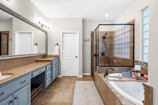 a spacious bathroom with a double vanity sink large mirror and a bathtub
