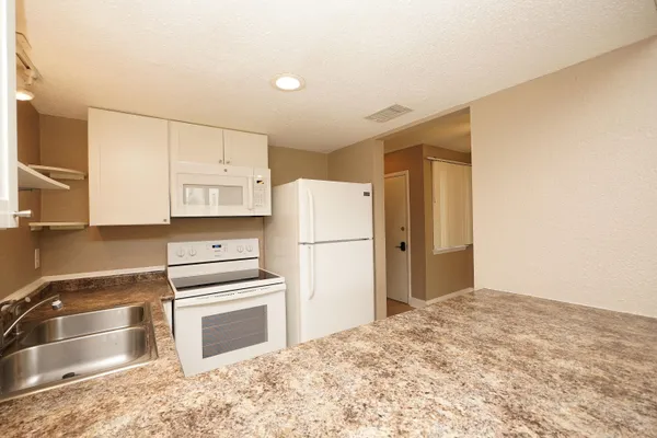 a kitchen with granite countertop a refrigerator and a stove top oven