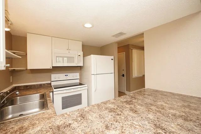 a kitchen with granite countertop a refrigerator and a stove top oven