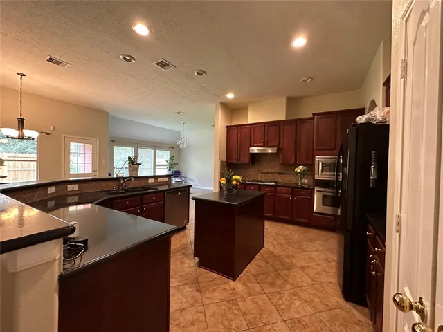 a kitchen with kitchen island a counter top space a sink stainless steel appliances and cabinets