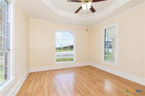 an empty room with windows and ceiling fan