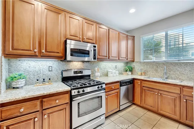 a kitchen with granite countertop cabinets stainless steel appliances a sink and window