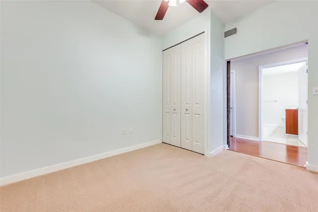 an empty room with ceiling fan and window
