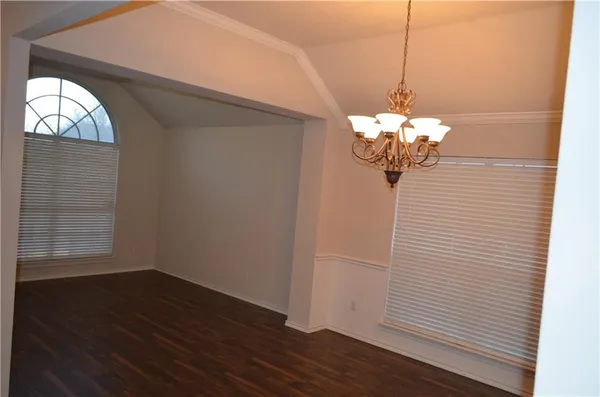 an empty room with wooden floor cabinet and windows