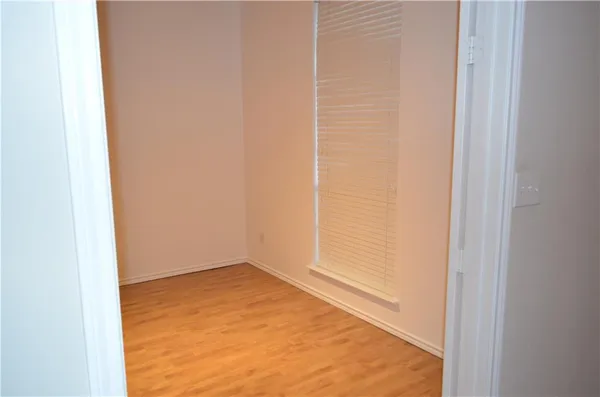 a view of an empty room with wooden floor and a fireplace