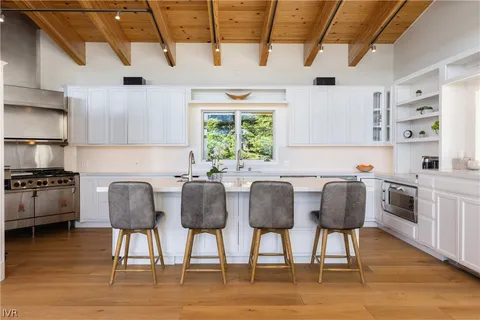 a kitchen with stainless steel appliances granite countertop a table chairs sink and cabinets