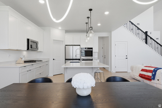 3364 Mapleton Hts Drive, Unit 101 Mapleton, UT 84664 - Photo 11 of 37 Contemporary open-concept kitchen featuring white shaker cabinetry, stainless steel appliances, a center island with pendant lighting, and light-tone flooring