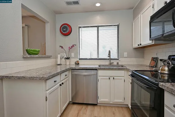 a kitchen with granite countertop a sink a stove and cabinets