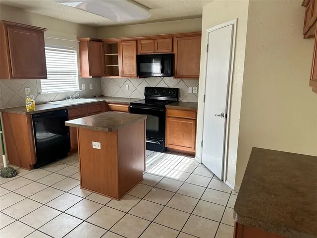 a kitchen with granite countertop a stove a sink and a microwave