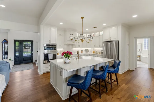 a kitchen with stainless steel appliances a dining table chairs stove and refrigerator