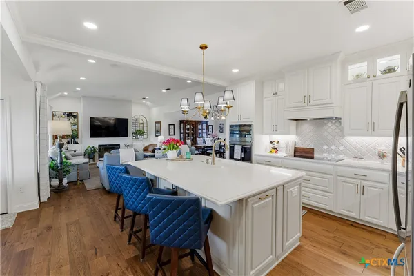 a kitchen with stainless steel appliances kitchen island granite countertop a sink dishwasher a dining table and chairs with wooden floor