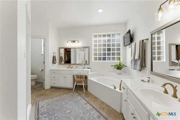 a spacious bathroom with a double vanity sink mirror and bathtub